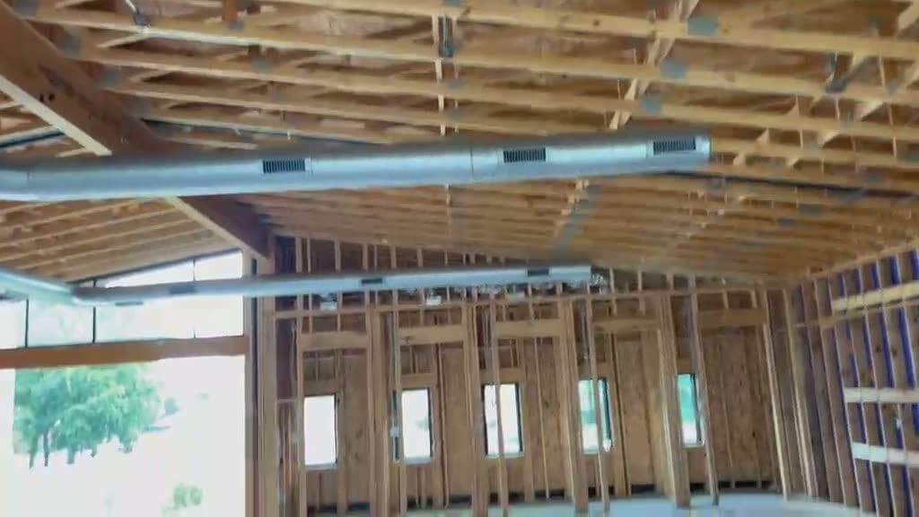 Rigid sheet-metal duct trunks running through the open framing of a new build.
